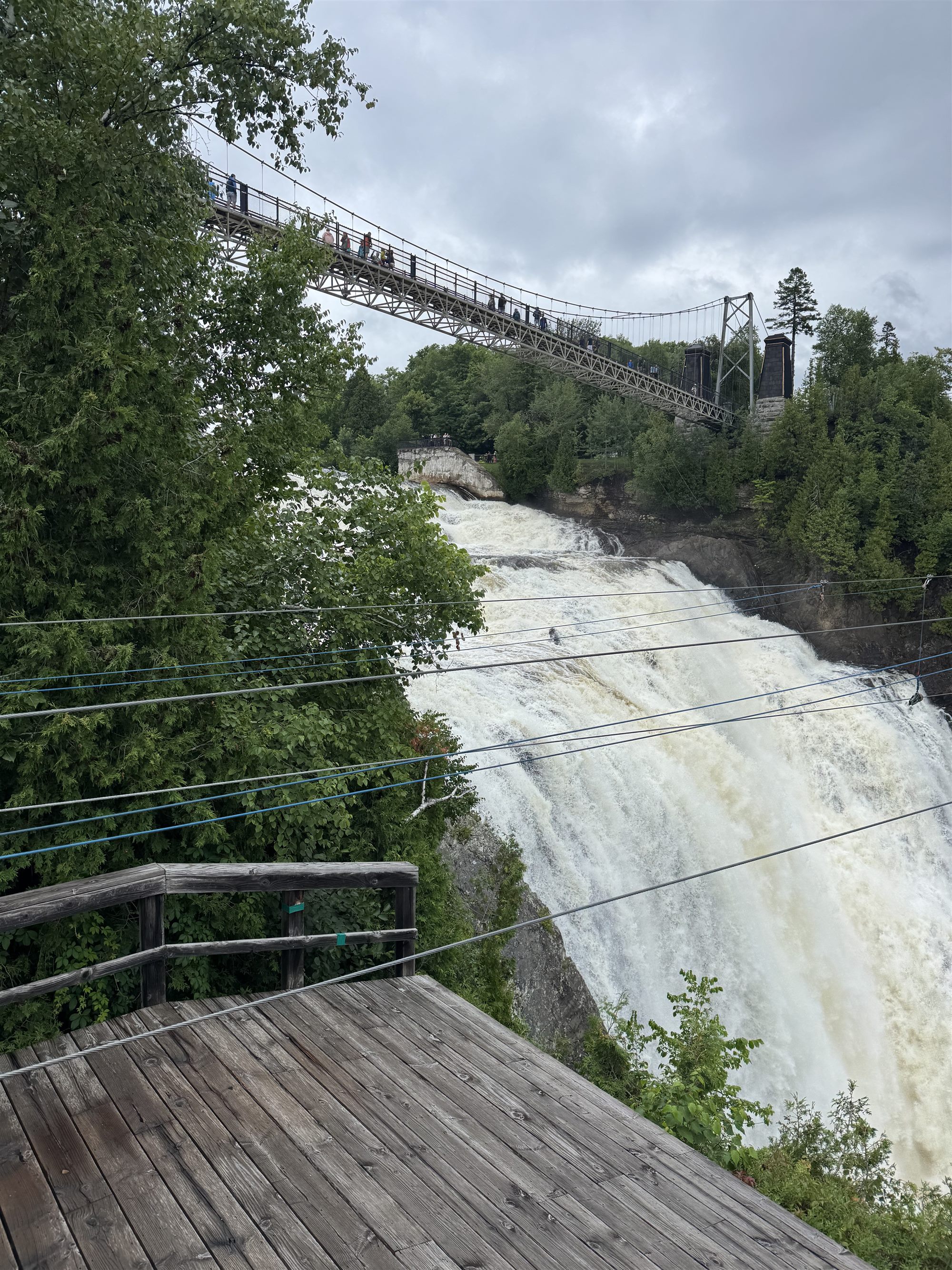 A waterfall in full flood beneath a suspension bridge